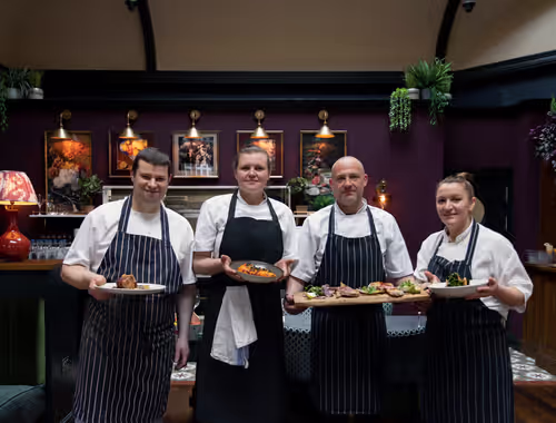 Young's kitchen staff members holding plates and trays of food in front of them